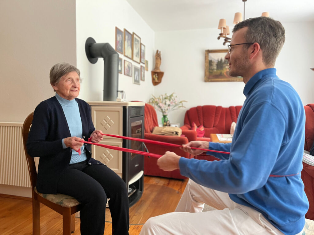Foto eines Physiotherapeuten, der im Rahmen der mobilen Geriatrischen Reha (MoGeRe) eine Patientin bei einer Übung in der Häuslichkeit anleitet.
