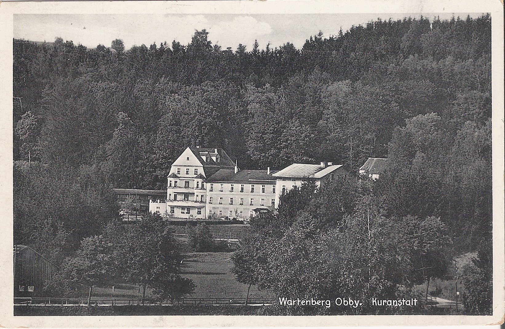 Historische schwarz-weiß Aufnahme einer Postkarte von 1926, auf der man das Altgebäude der Klinik Wartenberg umgeben vom Wald erkennen kann.
