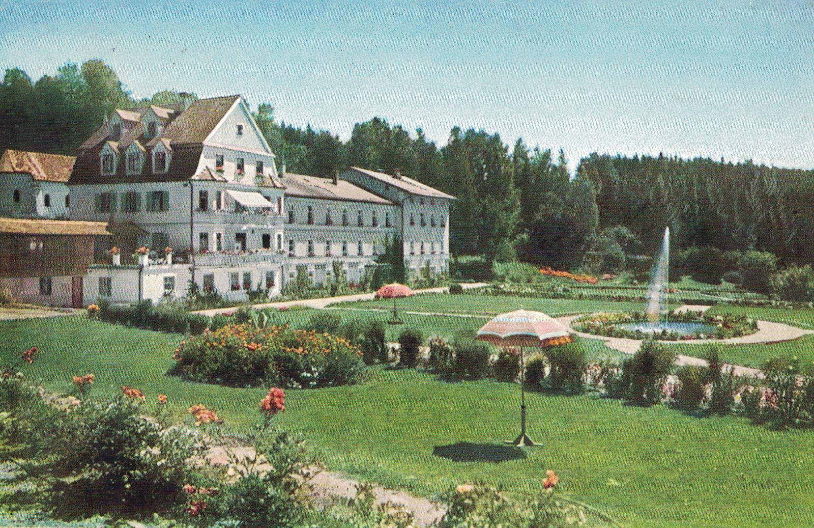 Historische Aufnahme einer Postkarte von 1936 mit dem Altgebäude der Klinik Wartenberg. In der Mitte des Geländes erkennt man den heute noch existierenden Springbrunnen. Die Parkanlage ist bepflanzt mit Sträuchern und Rosen.