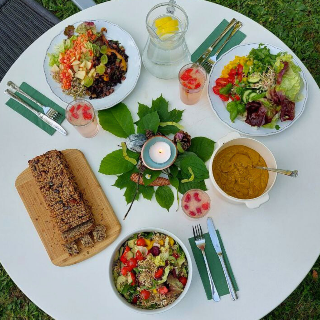 Bild eines aufgedeckten Tisches mit Salat und Körnerbrot. In der Mitte eine kleine brennende Kerze